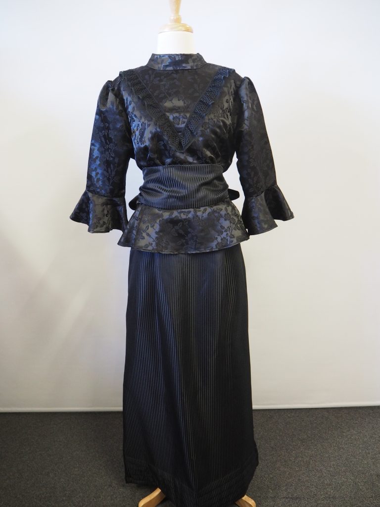Black Victorian ladies costume, includes a high necked blouse and bustled skirt