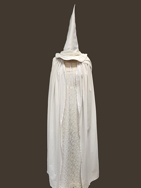 Image shows a Witch costume in white, including white cape, white witch hat and a lace dress. For hire from Acting the Part in Carlingford, Sydney.