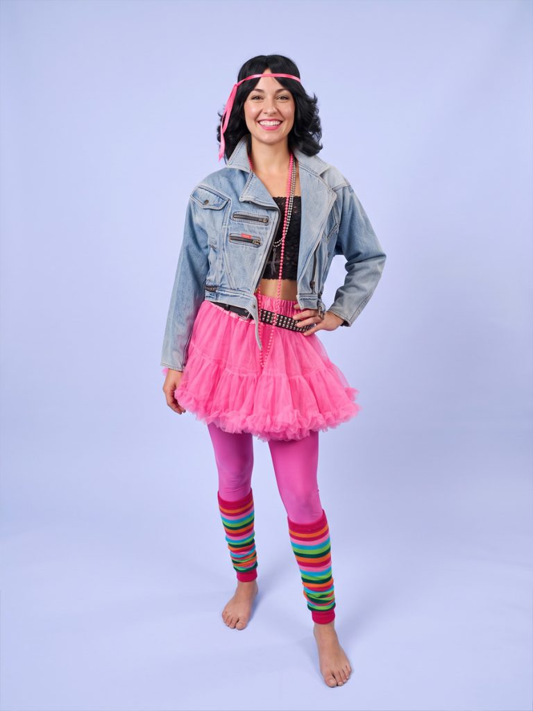 Image shows a mannequin dressed in a 1980s denim jacket, pink skirt, tights and legwarmers.